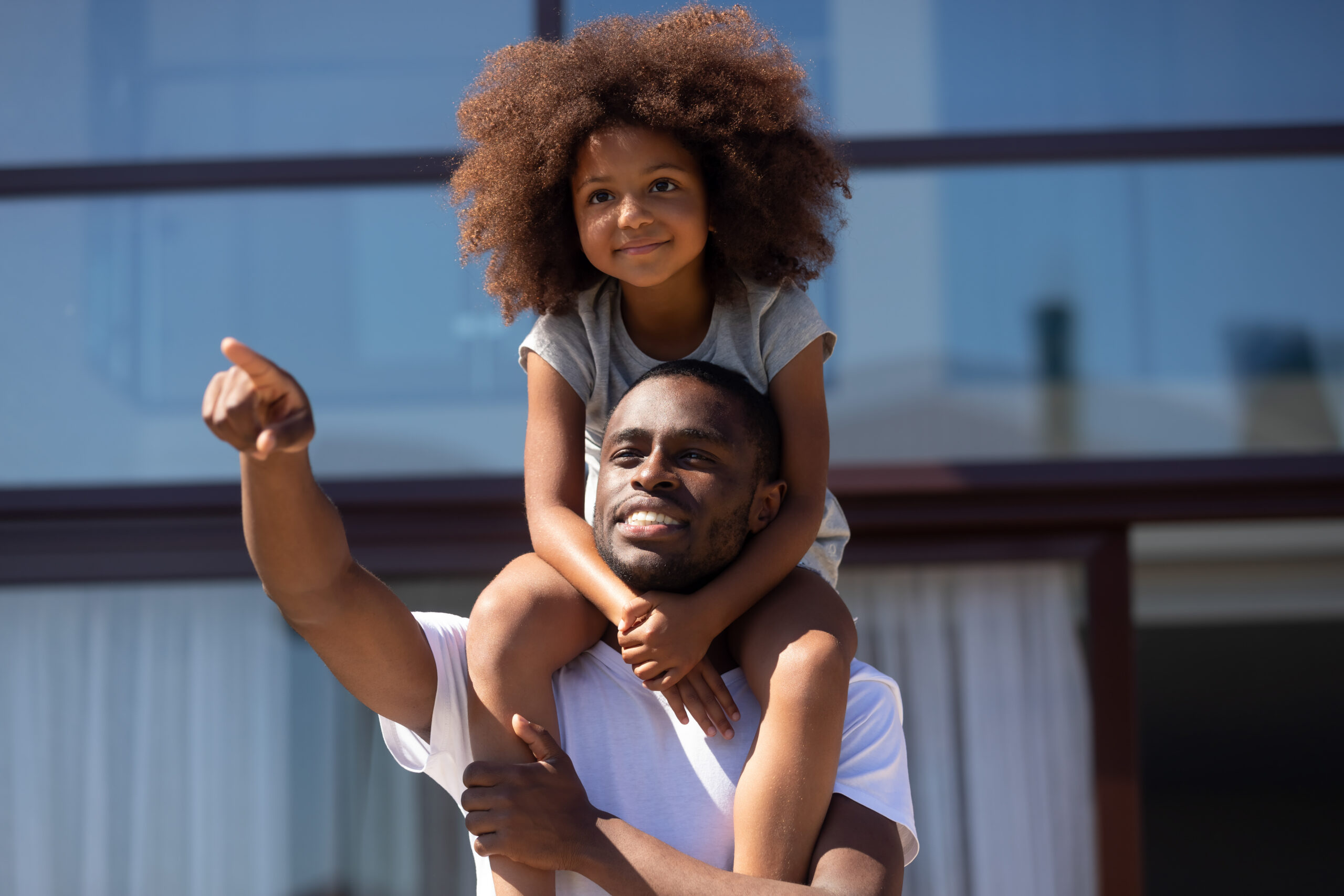 Young girl on adults shoulders outdoors exploring