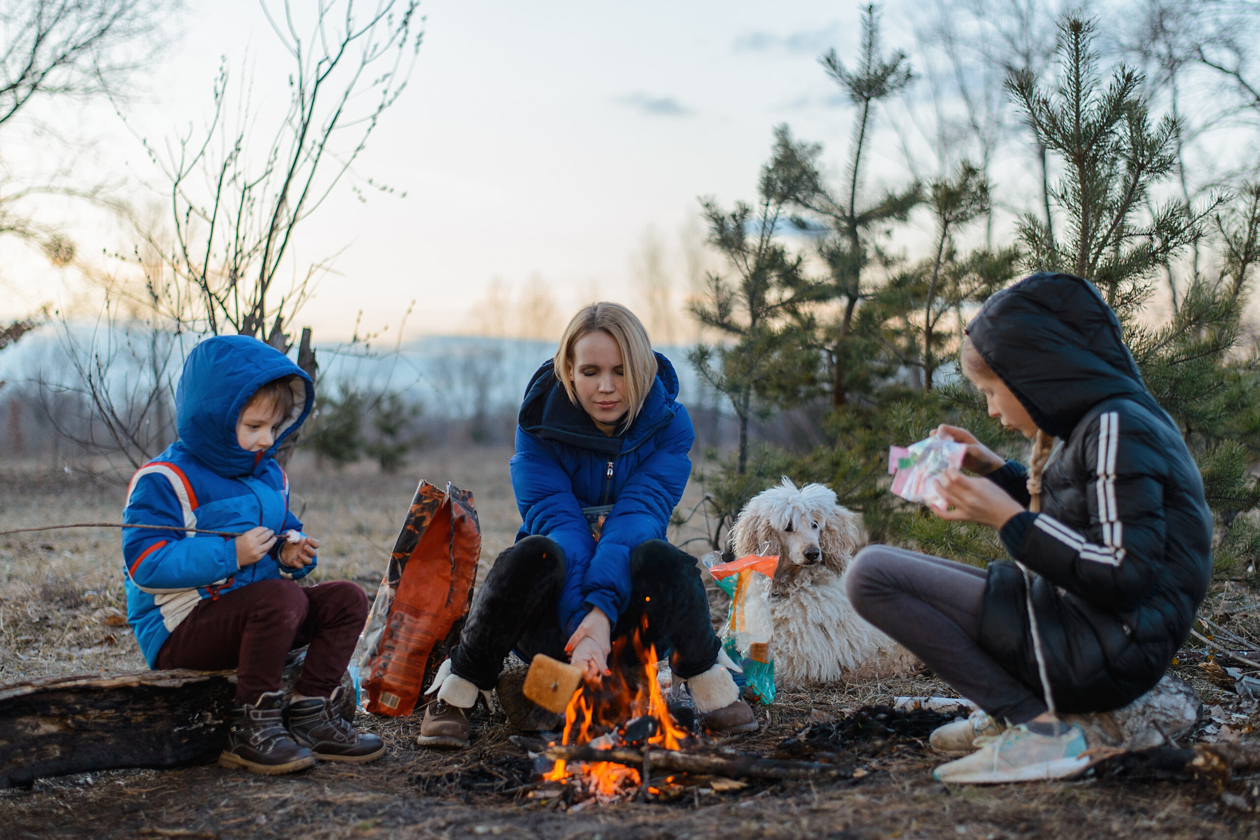 Woman and girls sitting around campfire