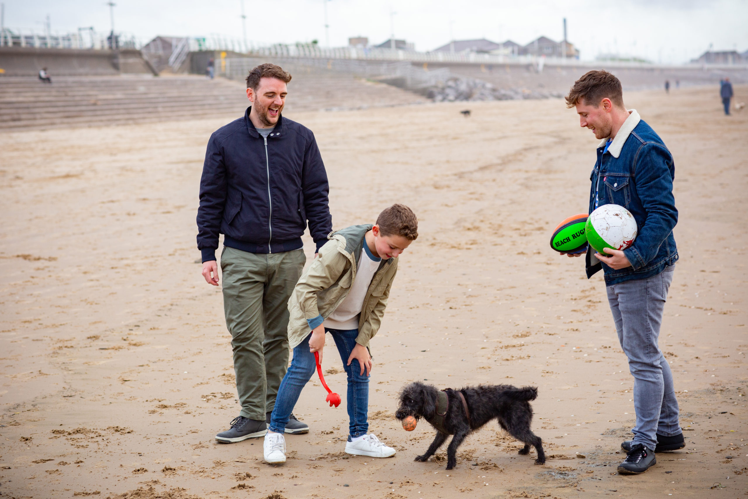 family playing with dog on the beach