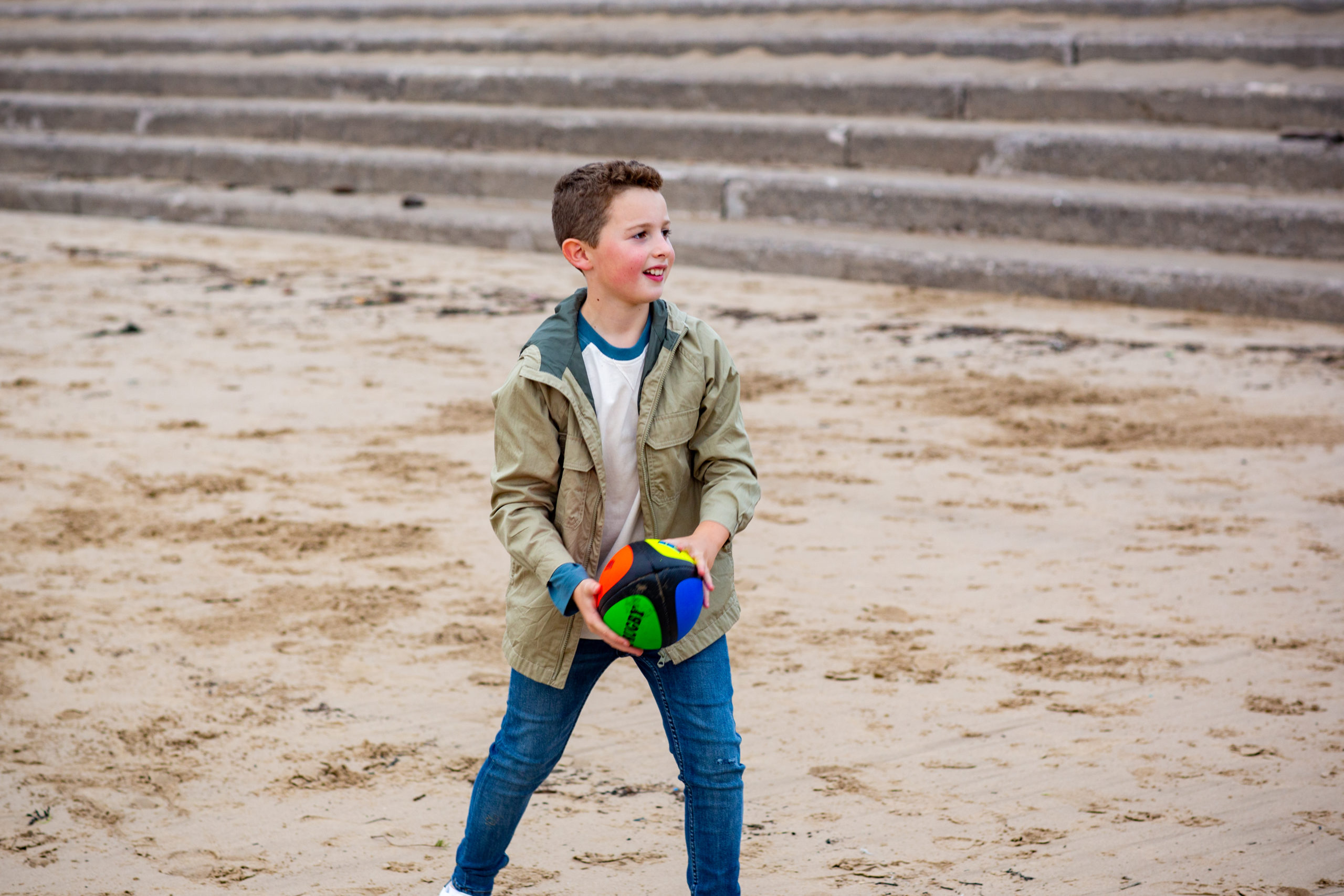 young boy playing with ball on the beach