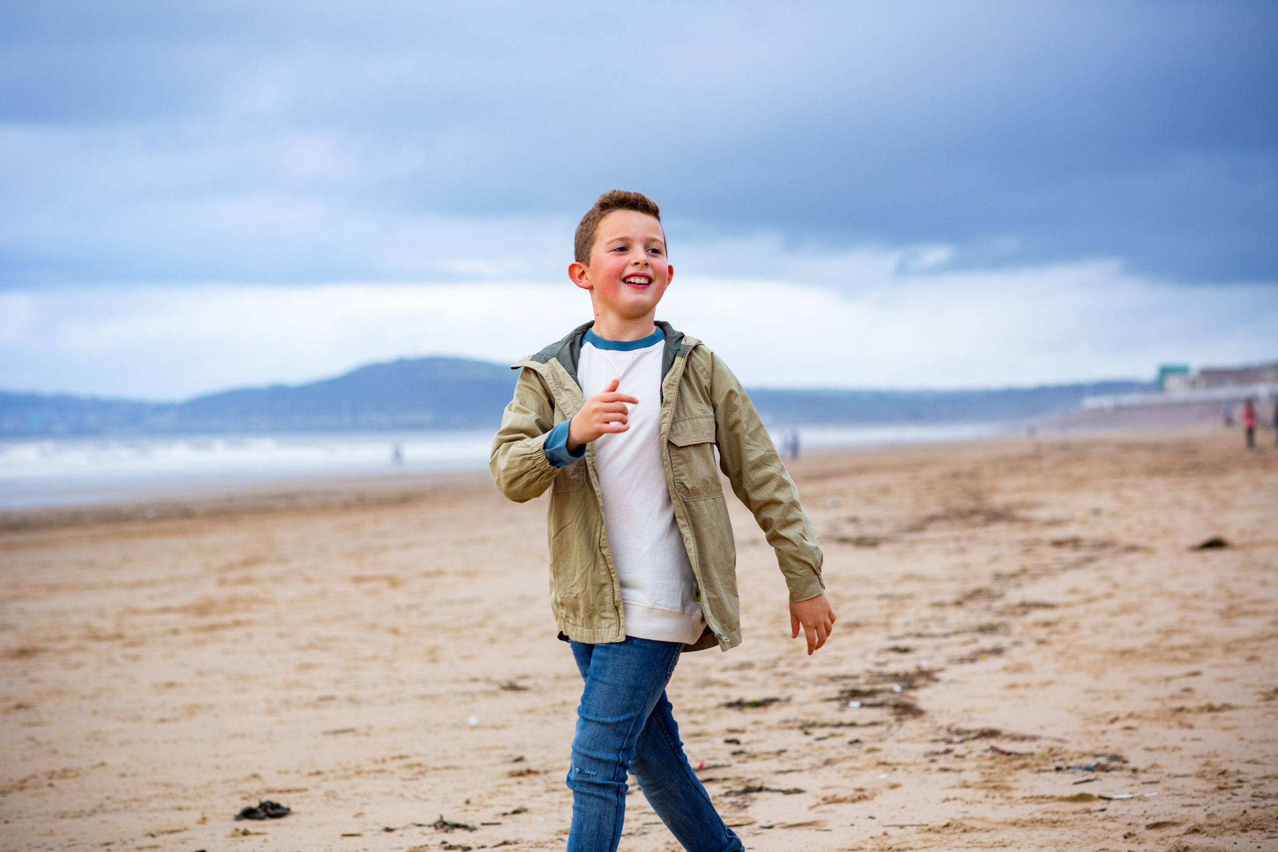boy smiling and running on the beach
